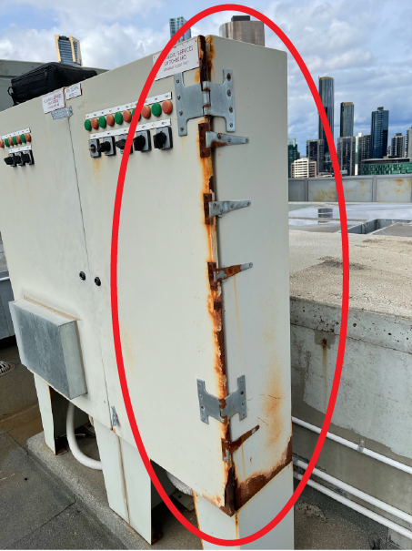 Red circle showing patch of rust in metal switchboard.